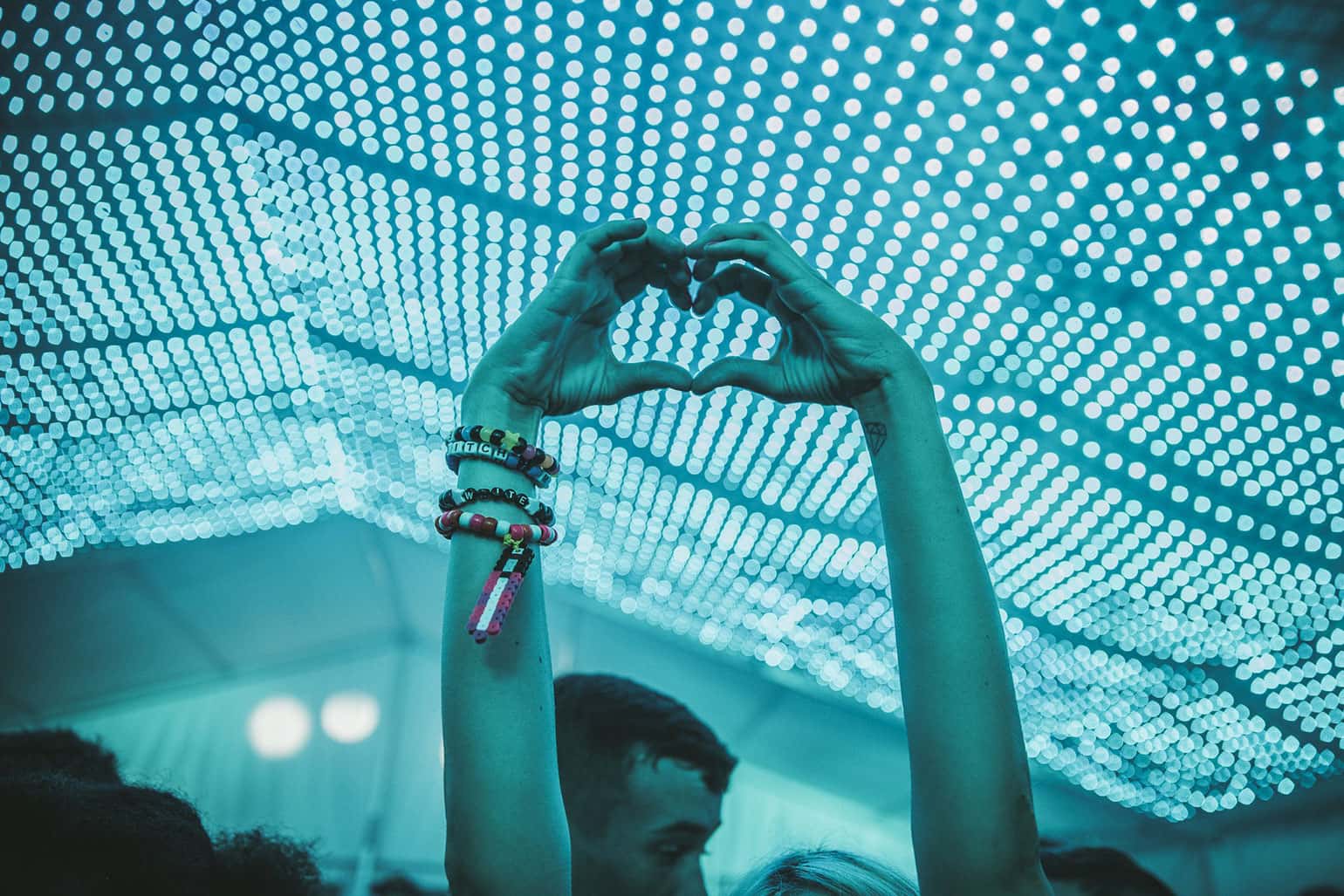 Young woman creates a heart with her hands under a lighted awning.