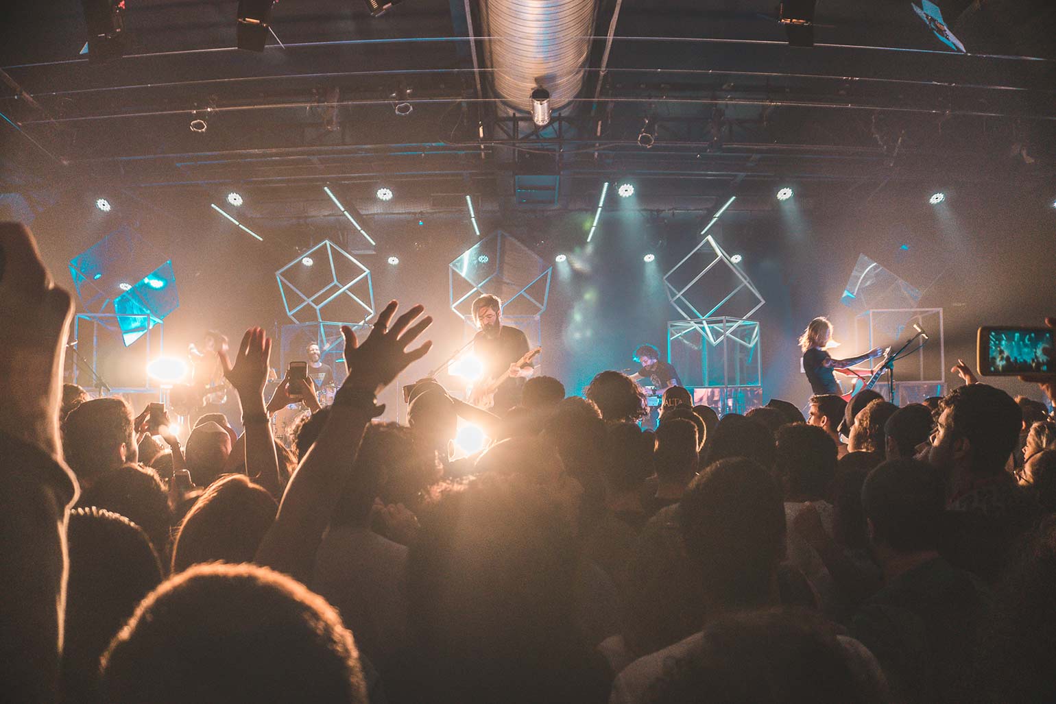 An audience cheering the band onstage at a live concert.