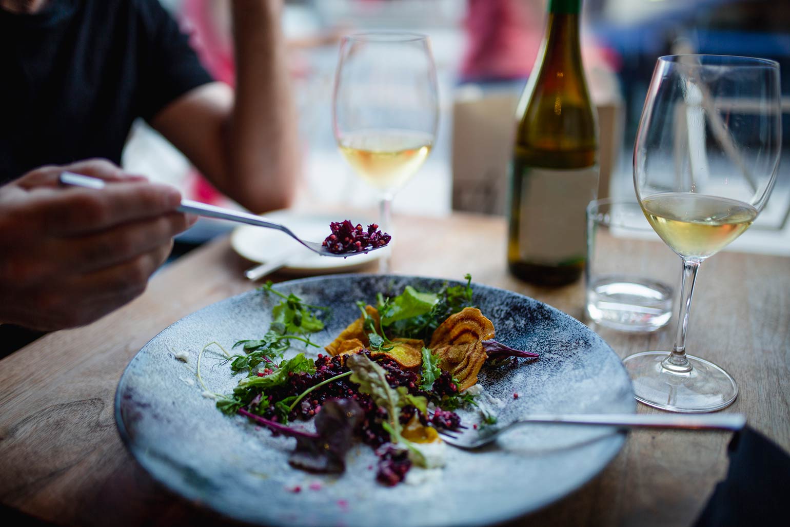 Une salade et une bouteille de vin partagées par deux personnes.