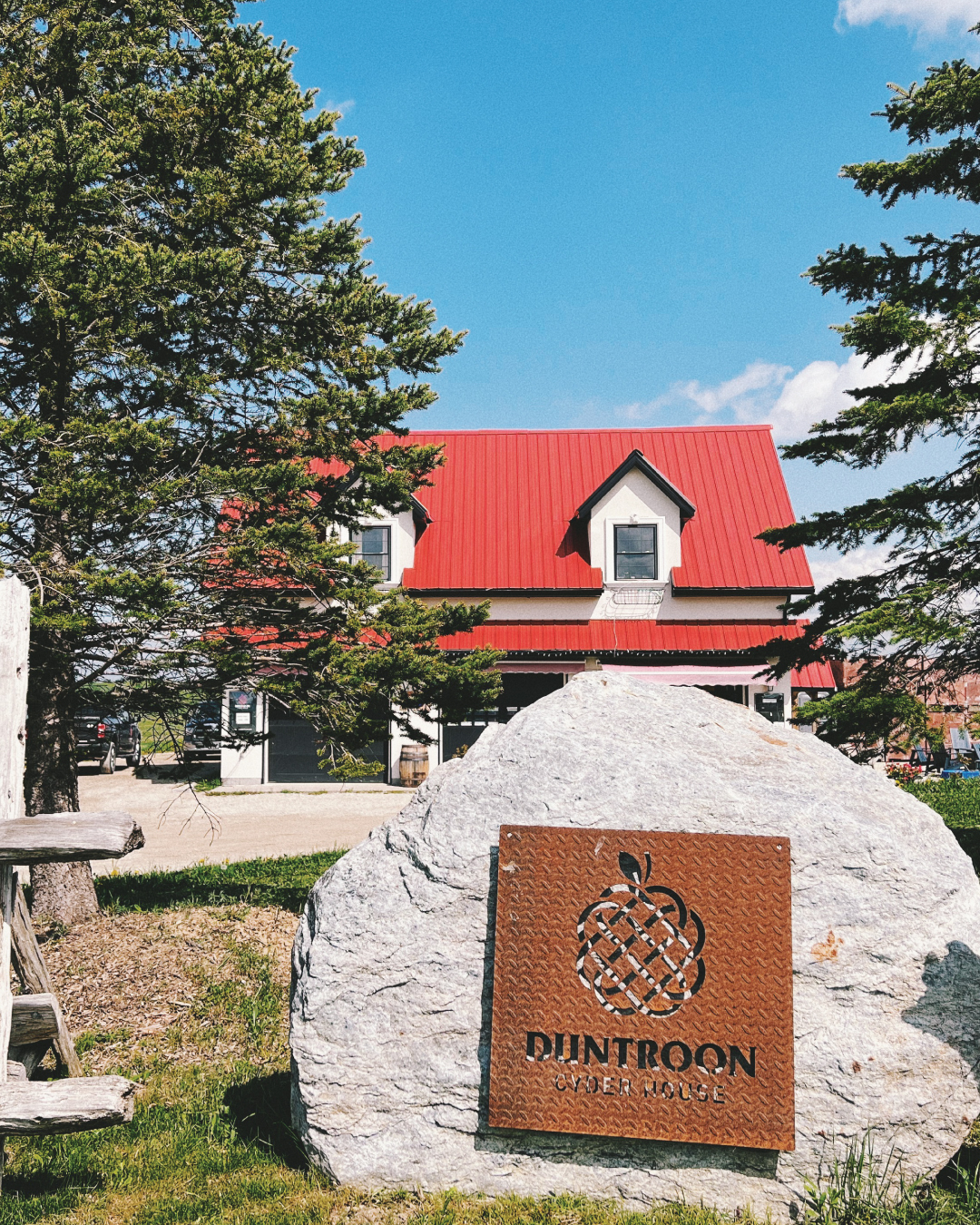 The Duntroon Cyder House, a farm house with a red roof, and a sign for the business hung on a rock