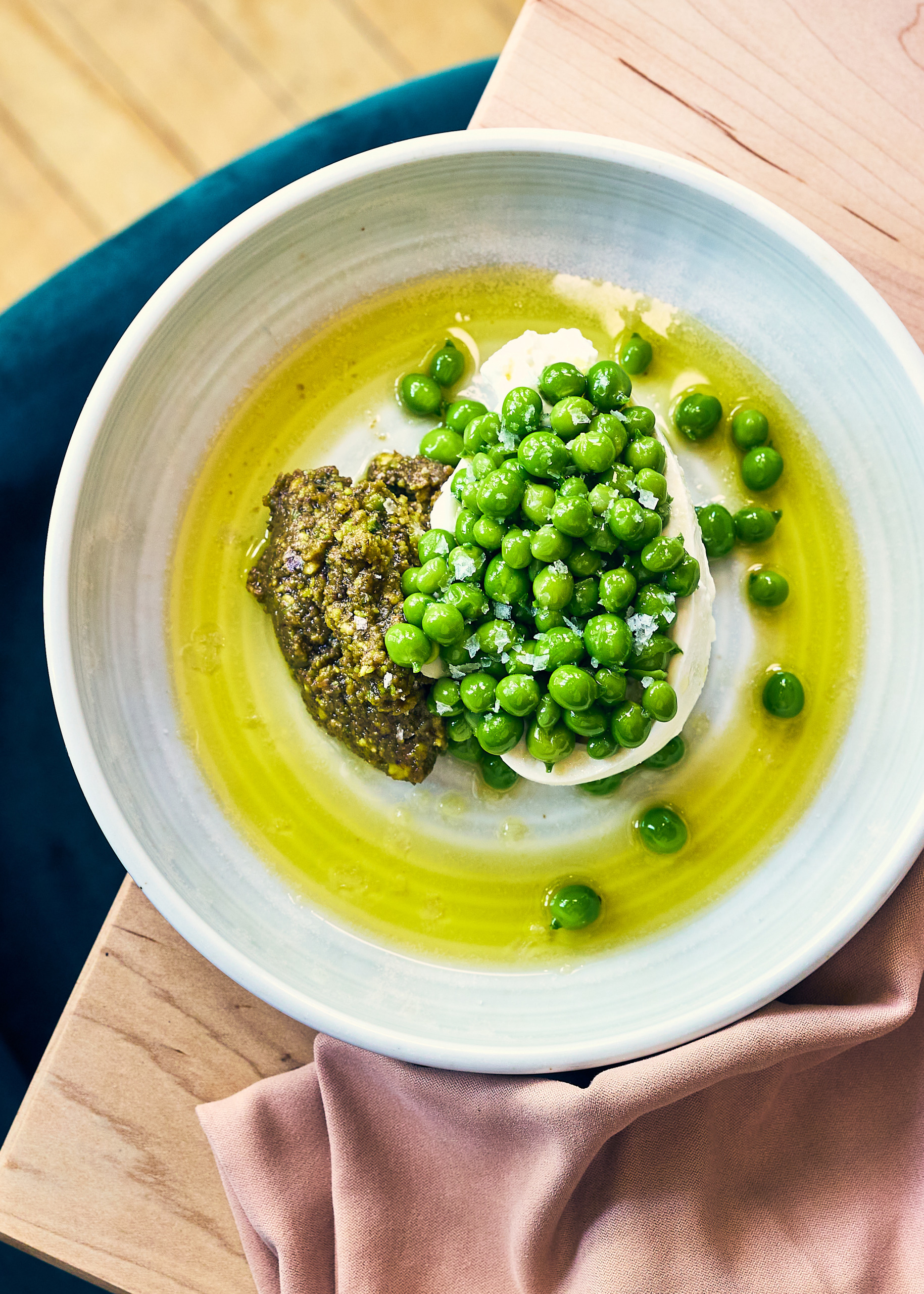 Looking down at a plate of mustard greens, snap peas and white cheese with aioli 