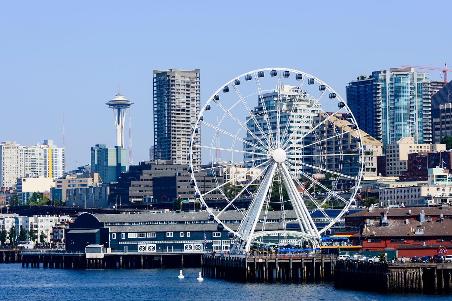 A view of downtown Seattle with the ferris wheel at the Seattle pier and the Space Needle national landmark.