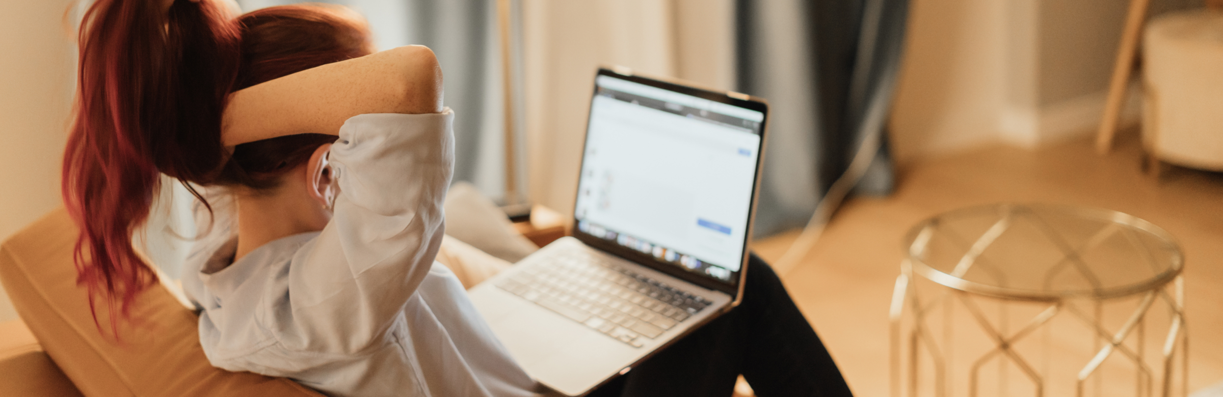 Person with hand to head appearing stressed while working at laptop in home office