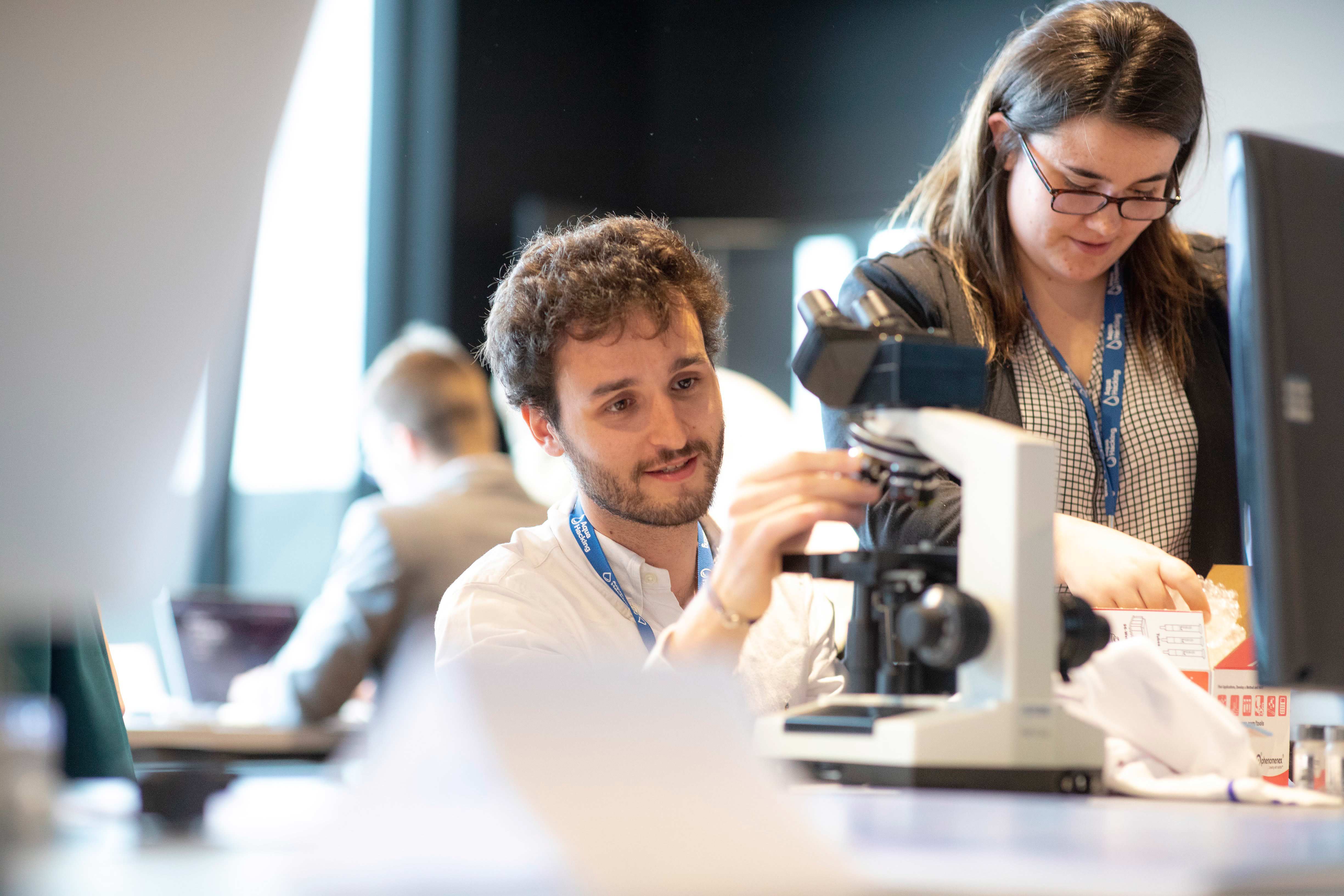 Young man using microscope during AquaHacking event