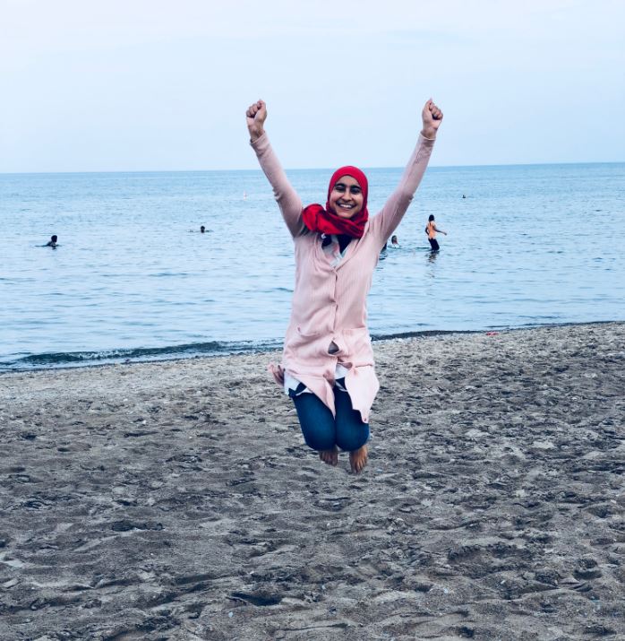Maria jumping joyfully on a beach.