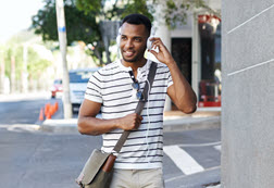 A man listening to music on headphones and walking on the street.