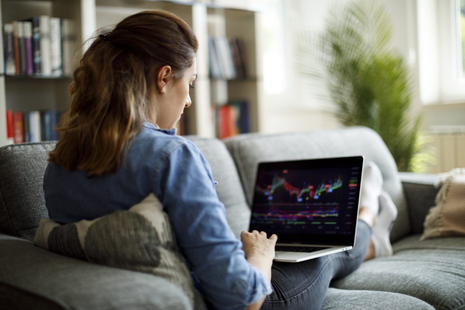 Girl on sofa looks at stock portfolio on laptop