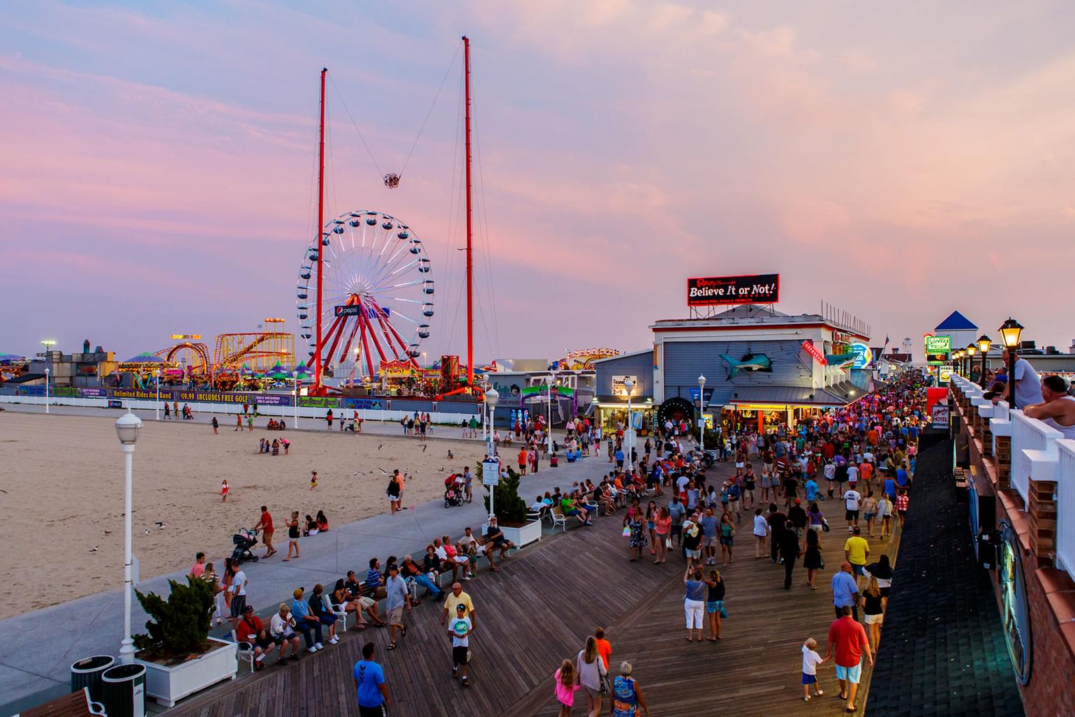 Dusk in Ocean City, Maryland with the boardwalk amusement park lit up.