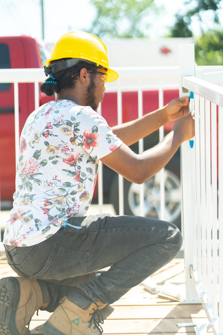 A male youth in a hardhat and an RTSC toolbelt driving nails into boards