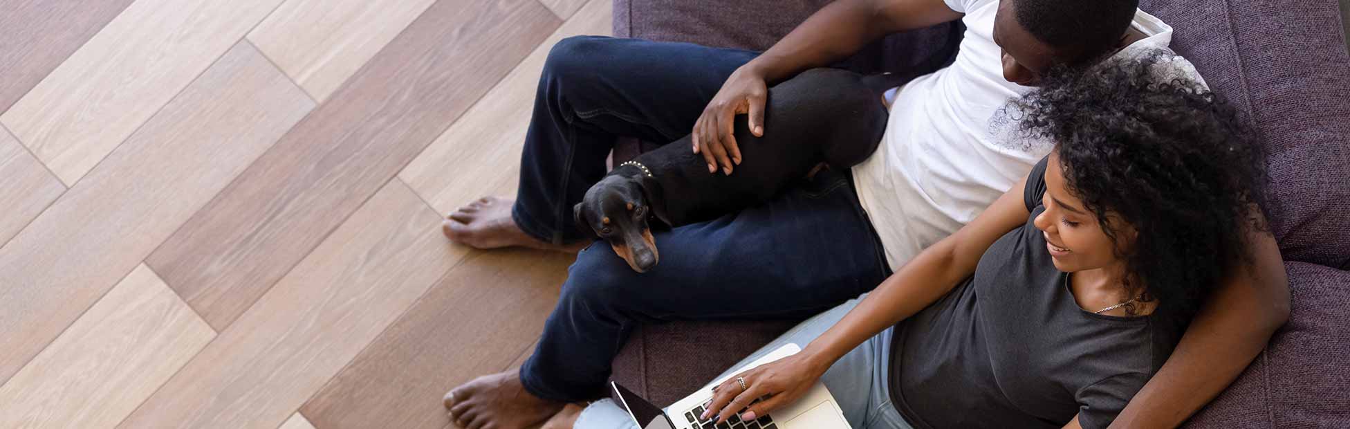 Top view of happy young couple online shopping sitting on sofa with pet