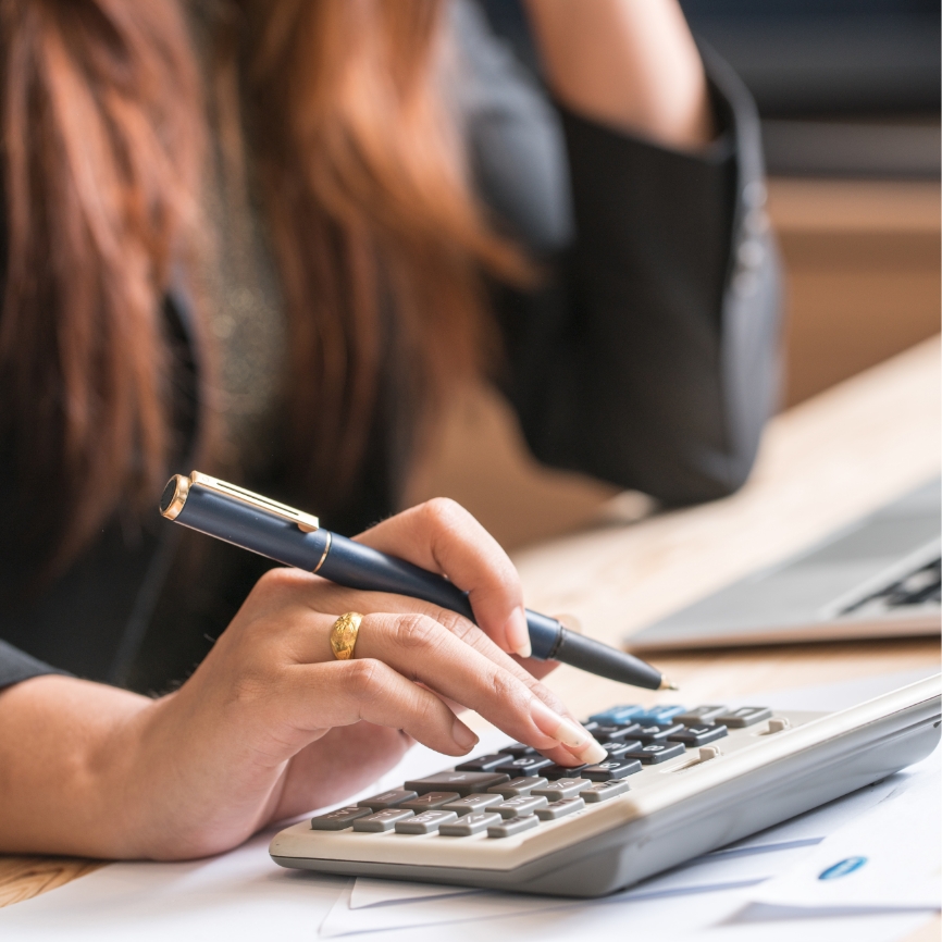 A women tallying numbers over a calculator.