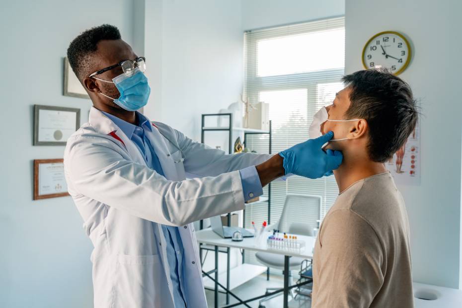 A male doctor doing an exam on a male patient in the clinic.