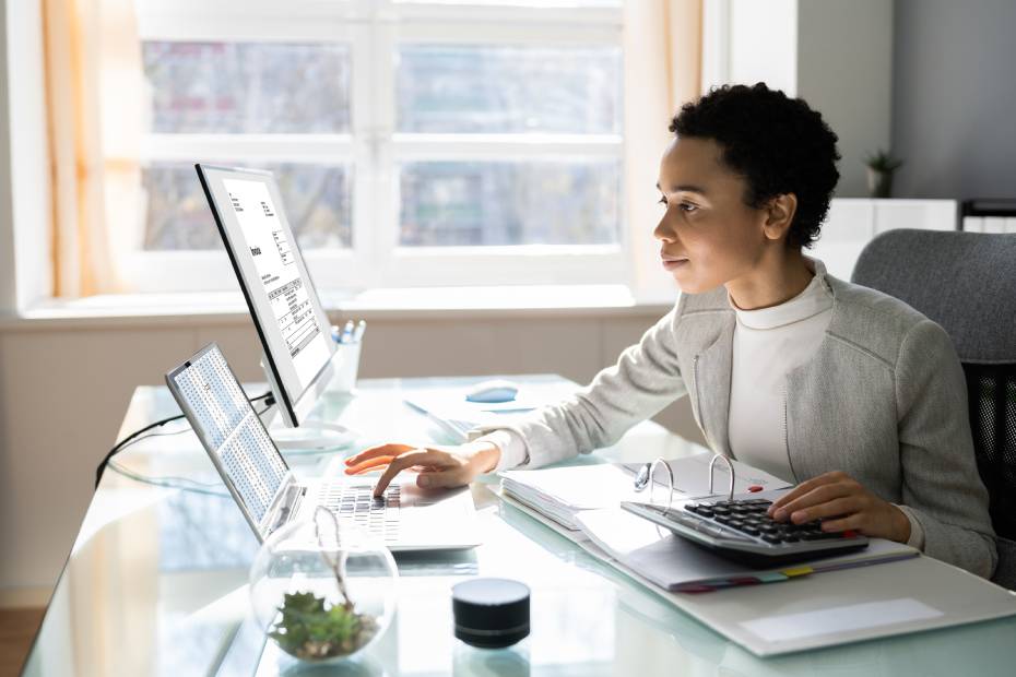 A female entrepreneur reviewing payment transactions on multiple computers
