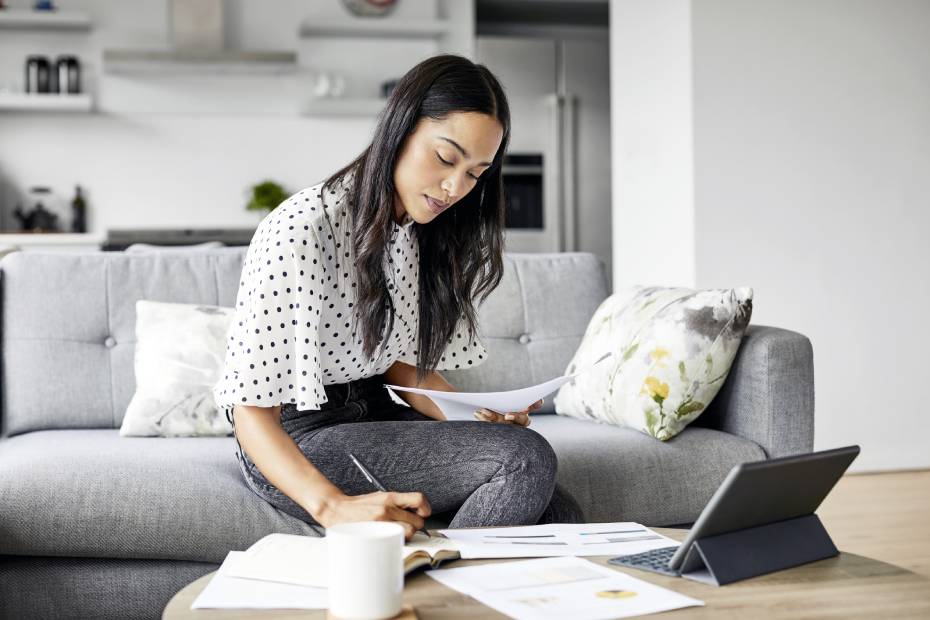 Young woman analyzing bills while writing in diary.