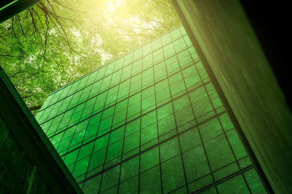 Eco-friendly building in the modern city. Sustainable glass office building with trees for reducing heat and carbon dioxide. Office building with a green environment.