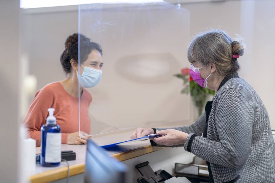 A clinic receptionist welcoming a female patirent