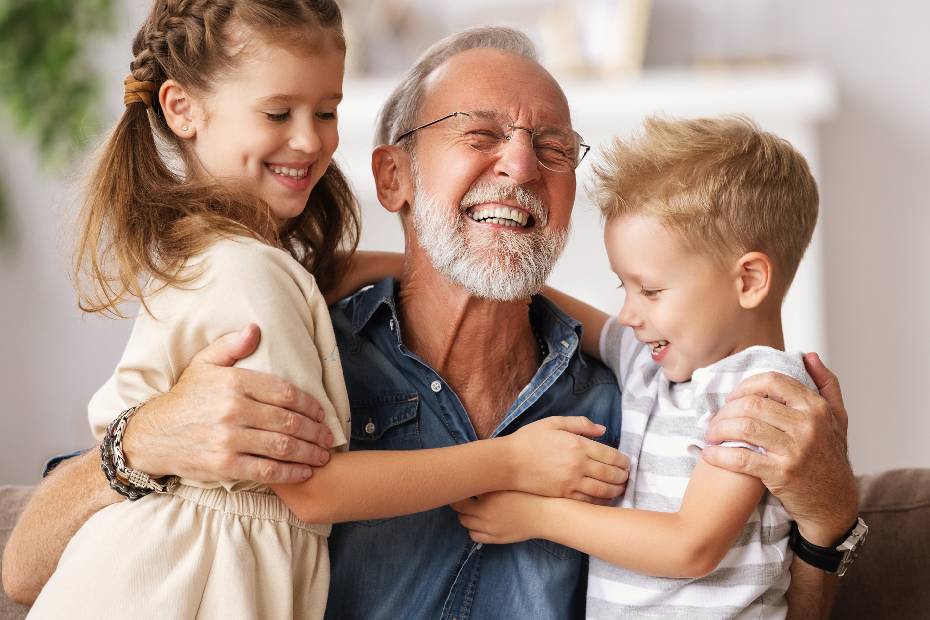 A picture showing a mature man playing his two grandchildren happily.