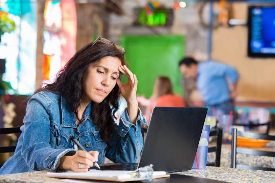 A female business owner making notes while working on a laptop