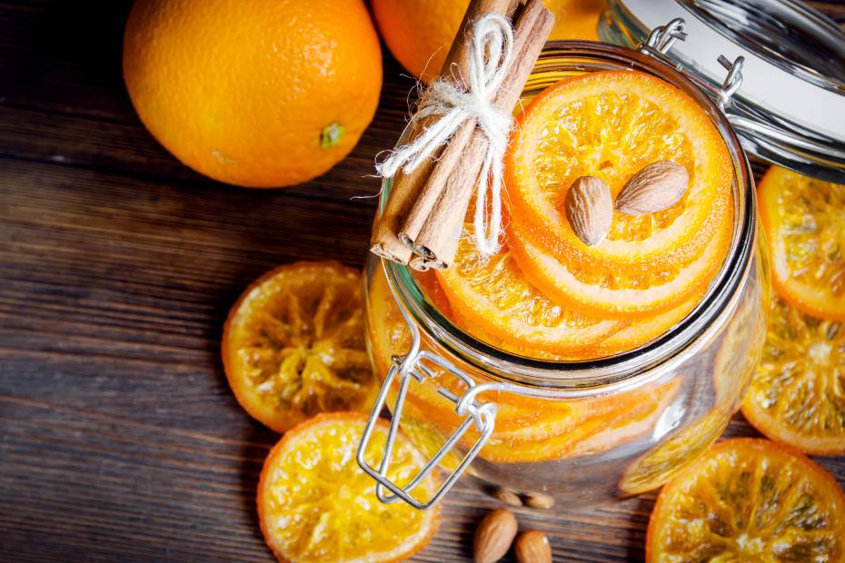 Candied oranges in a glass jar with cinnamon sticks and almonds.