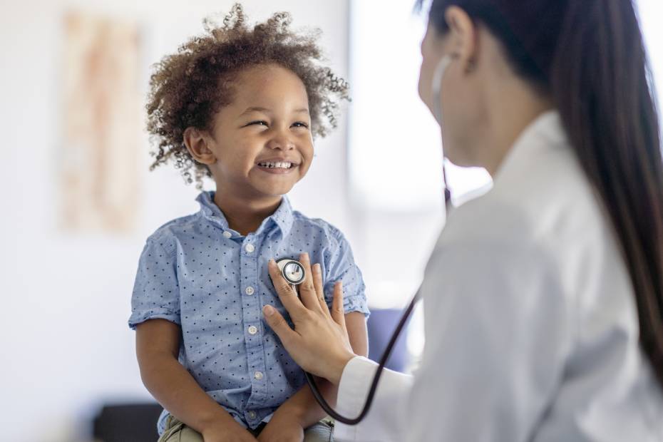 A female doctor listens to a little boy's heart with her stethoscope.