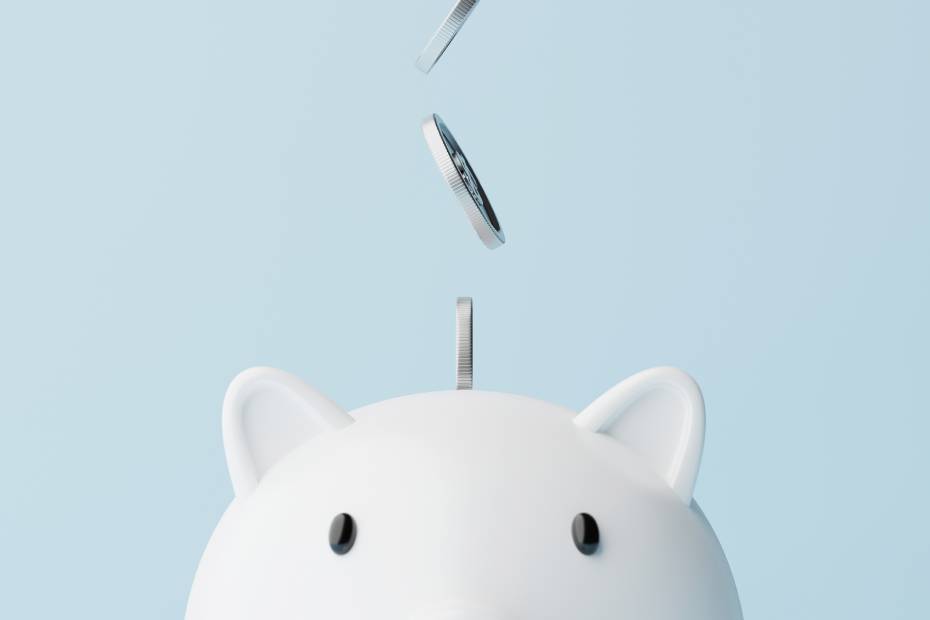 Close up of a piggy bank with coins falling into it.