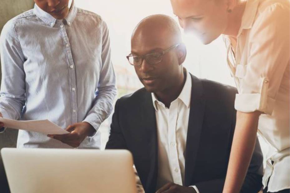 Man and colleagues looking at a laptop screen