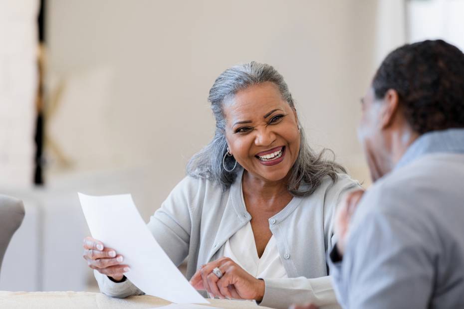 A happy senior woman smiling at her financial advisor, holding a copy of her financial plan.