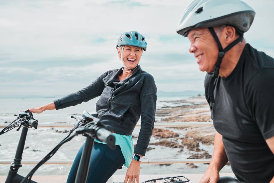 Mature laughing couple on electrical bikes by a lake