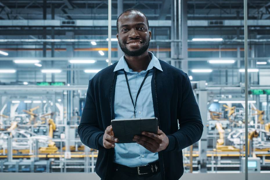 A smiling engineer in an EV factory, holding a tablet