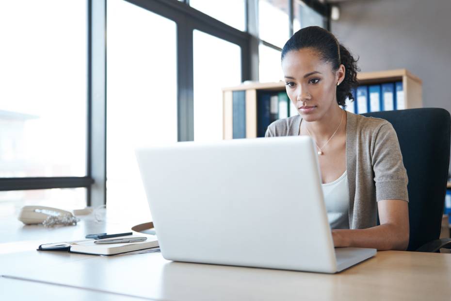 A young female investor with a serious expression reviewing her investments on a laptop