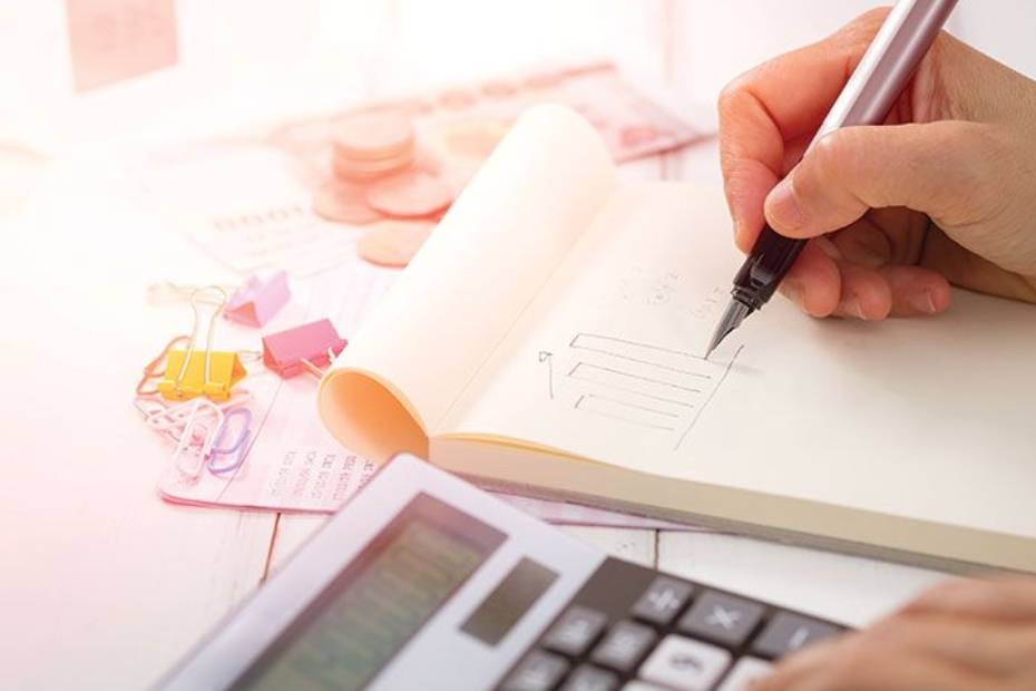Hands writing budget calculations on a page