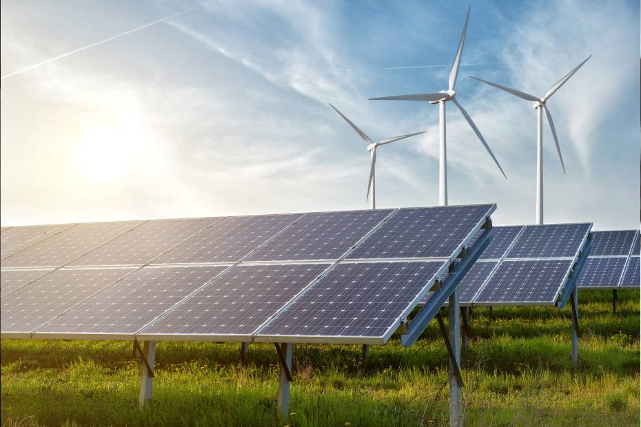 A renewable energy farm with rows of solar panels and wind turbines.