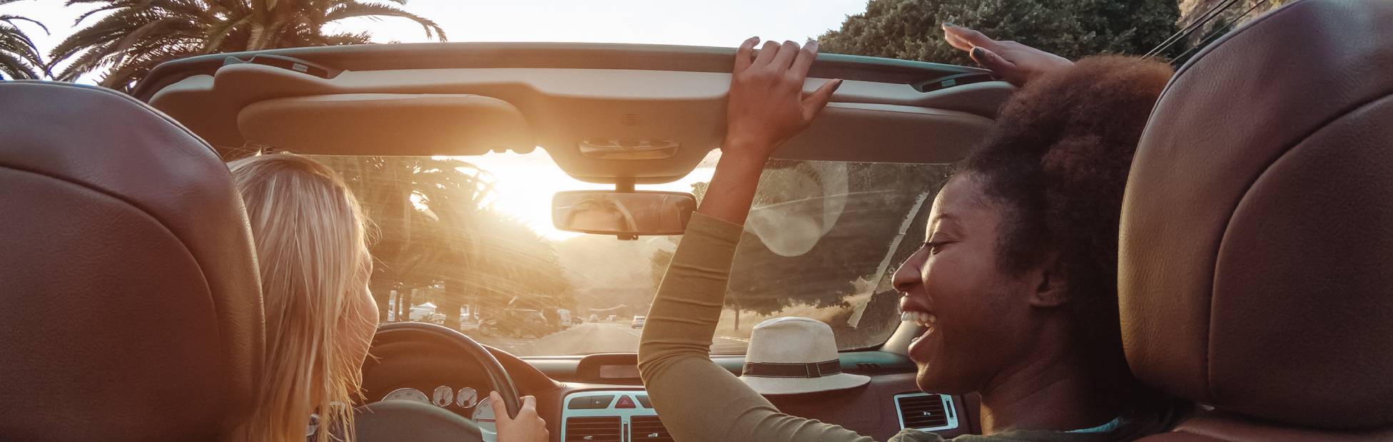 Two friends driving with their car top down