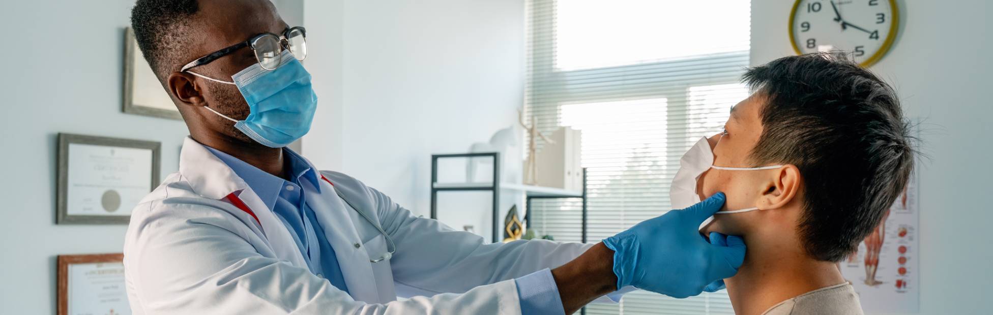 A male doctor doing an exam on a male patient in the clinic.