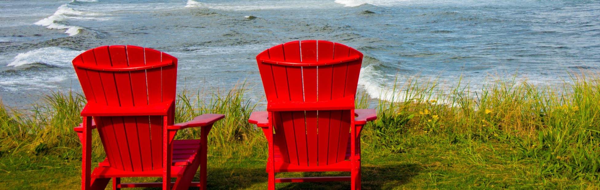 2 red Adirondack chairs overlooking the beach in PEI