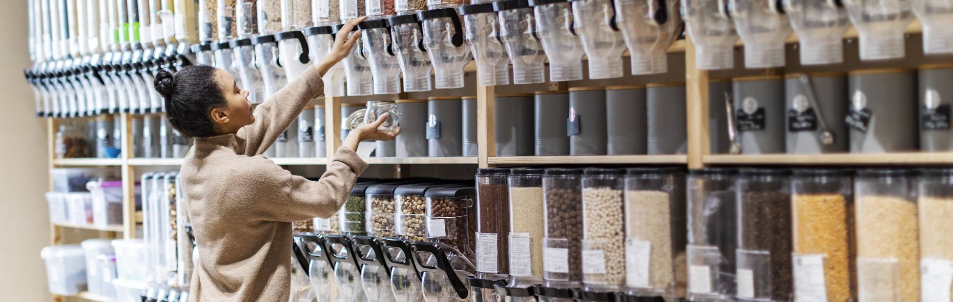 A young female customer filled a container with dried beans in a co-op.