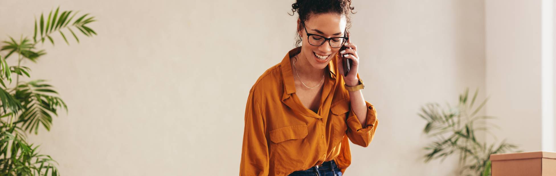 Female business owner on telephone packing boxes for shipping