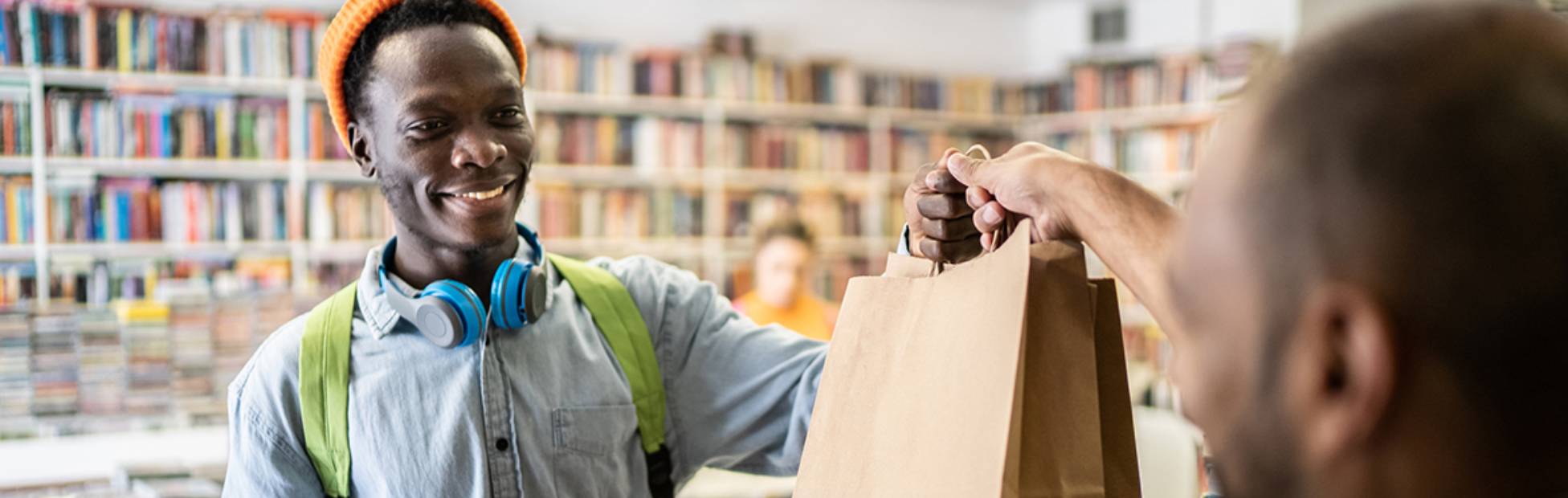 A cashier passes a bag to a customer in a store.