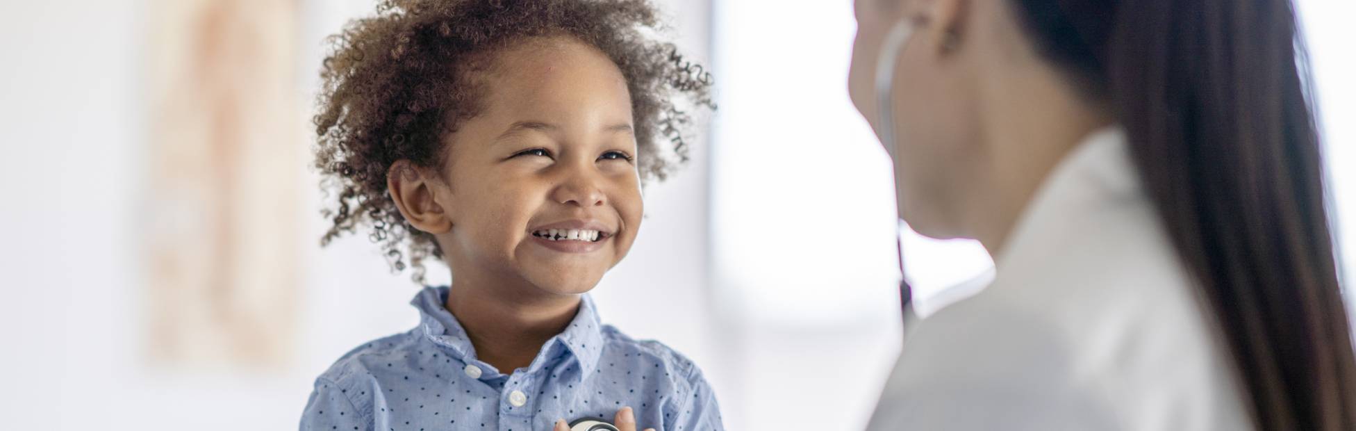 A female doctor listens to a little boy's heart with her stethoscope.