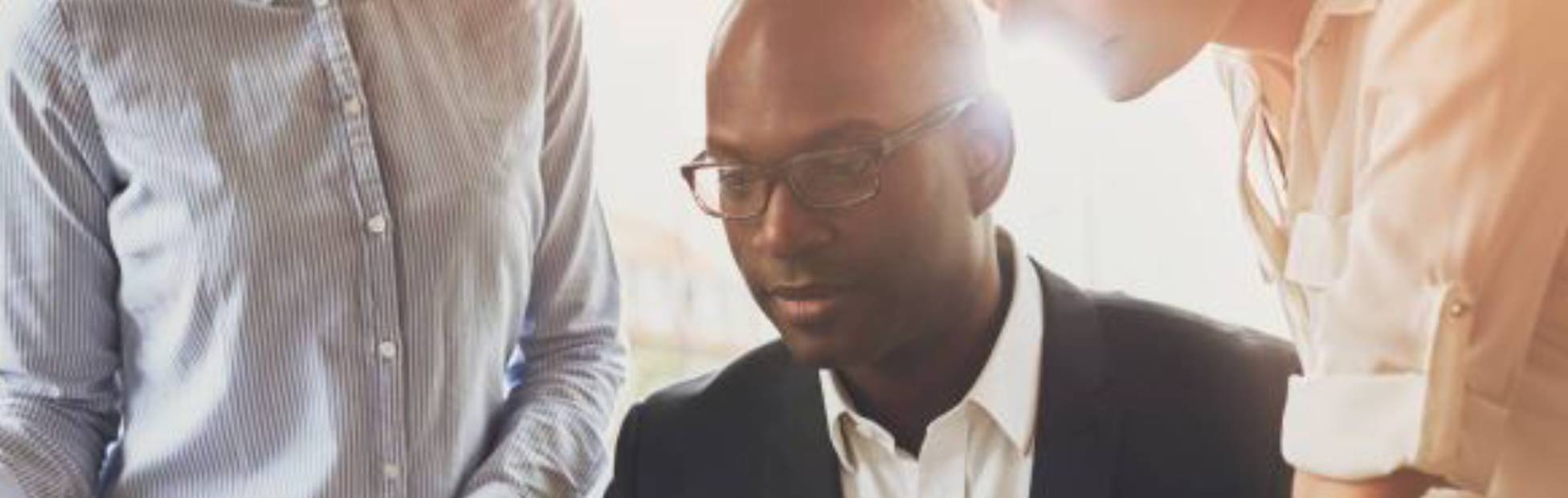 Man and colleagues looking at a laptop screen