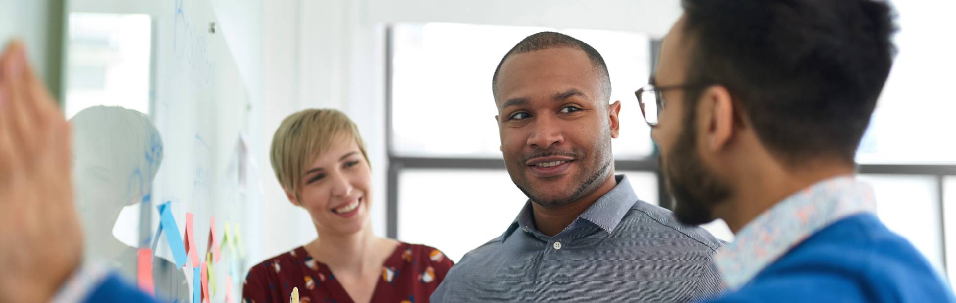 Three entrepreneurs standing in front of a whiteboard with sticky notes