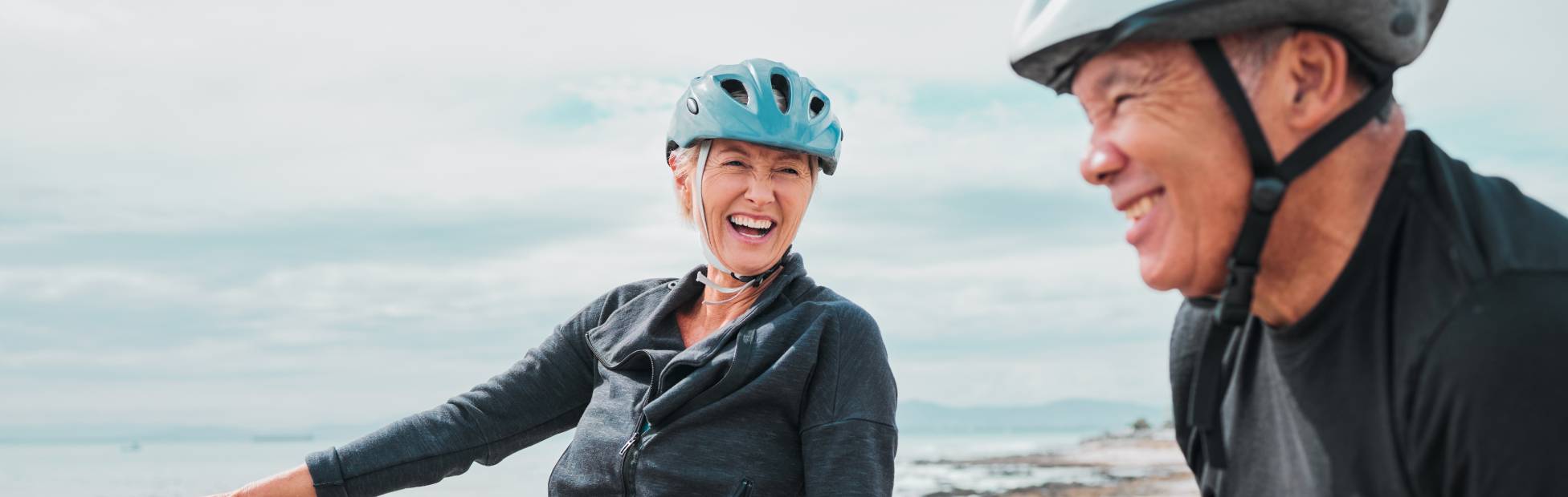 Mature laughing couple on electrical bikes by a lake
