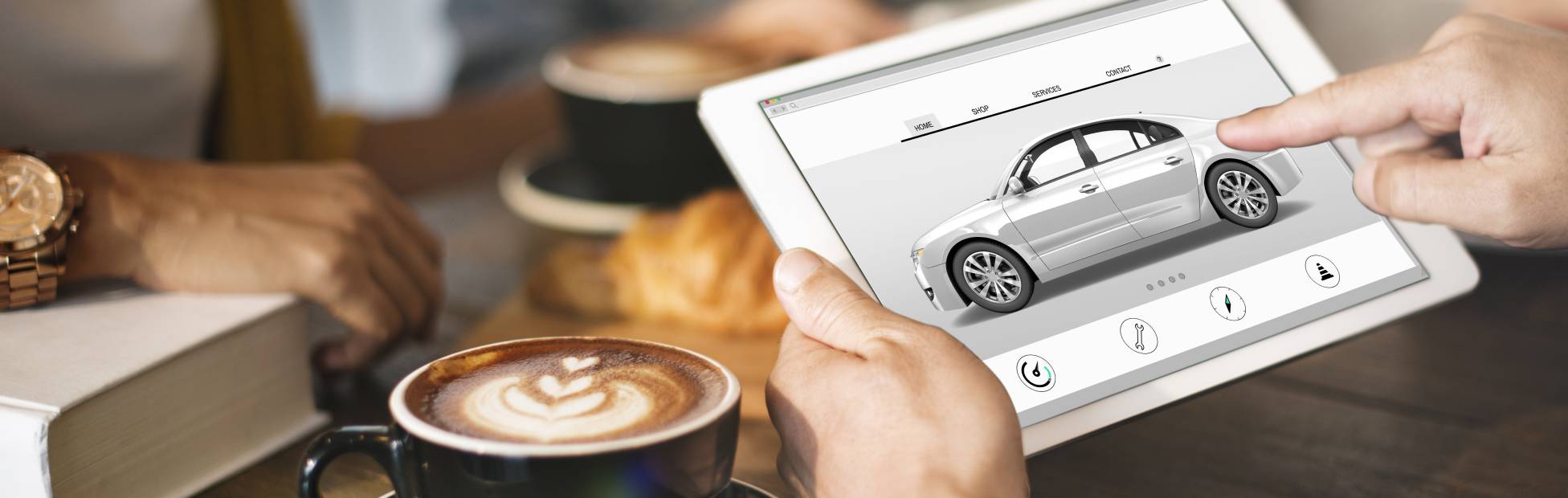 A driver in a coffee shop, researching electric vehicles on a tablet