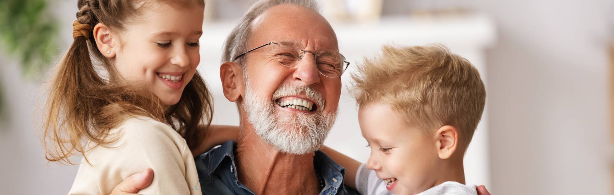 A picture showing a mature man playing his two grandchildren happily.