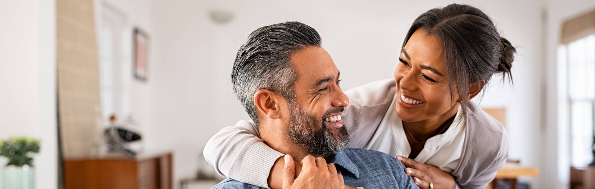 A picture showing a woman hugging her husband from the back.