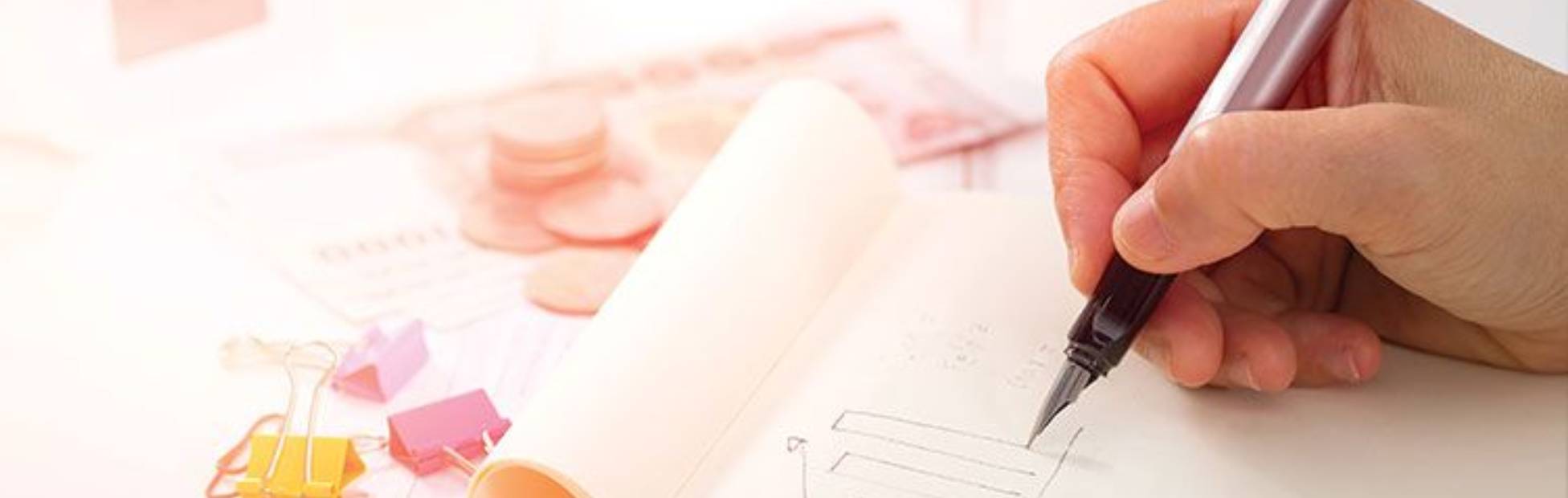 Hands writing budget calculations on a page