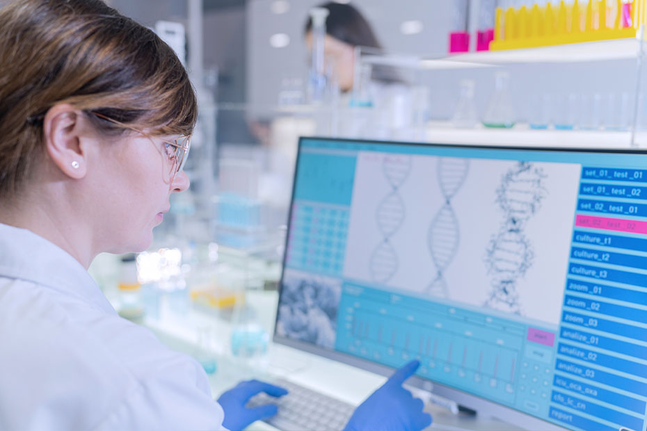 A medical geneticist studying the DNA sequence visible on the screen.