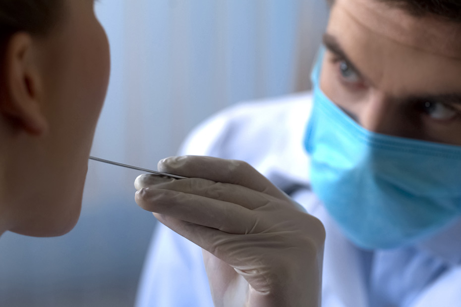 An otolaryngologist examining a female patient throat