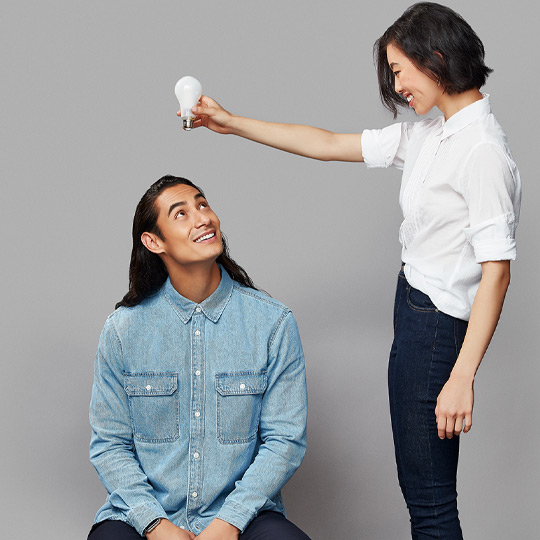 A lady holding a lightbulb above a mans head