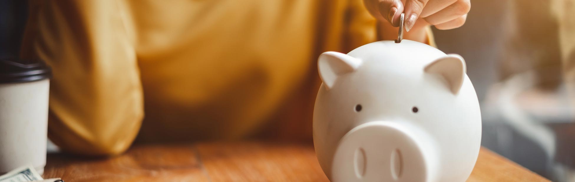 A young girl deposits money in a piggy bank.